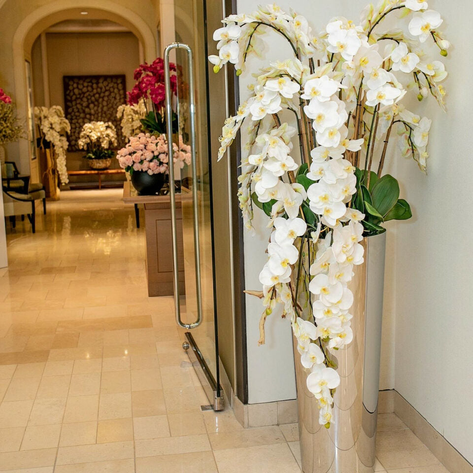Orquídeas Phalaenopsis en cascada sobre un cono cónico de acero inoxidable pulido