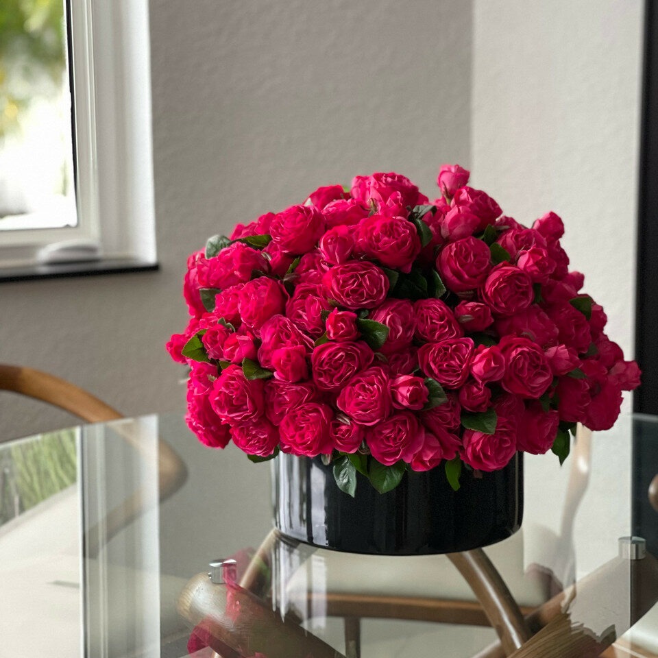 Roses anglaises rose foncé dans un vase en verre rouge