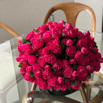 Roses anglaises rose foncé dans un vase en verre rouge