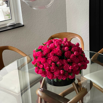 Roses anglaises rose foncé dans un vase en verre rouge