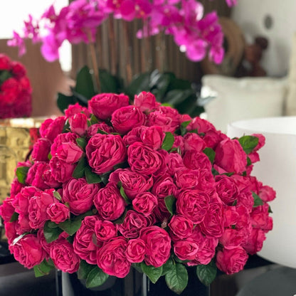 Roses anglaises rose foncé dans un vase en verre rouge