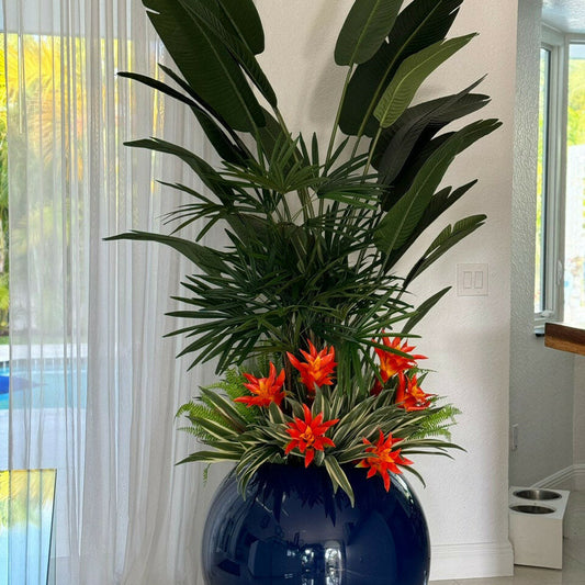 Mezcla de plantas tropicales en maceta esférica de color azul cobalto.