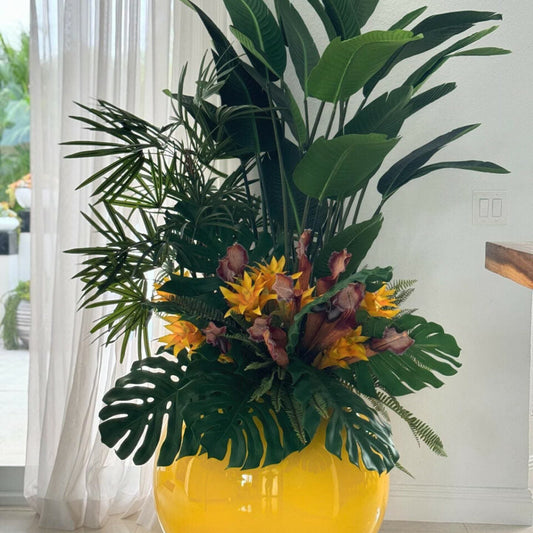 Mezcla de plantas tropicales en maceta globo amarilla.